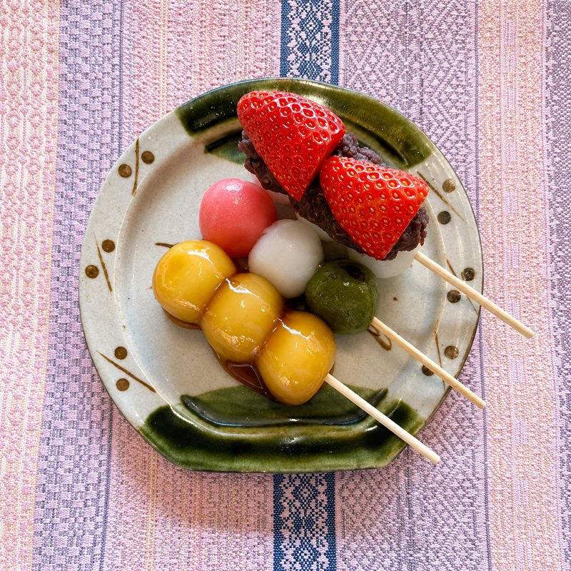 A plate of dango — chewy rice-flour dumplings on skewers with red bean and fresh strawberry